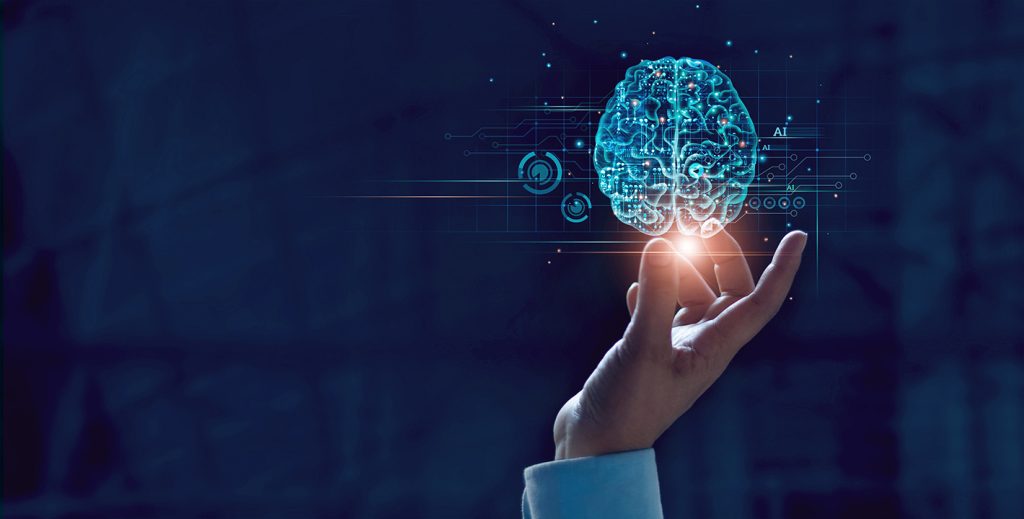 A hand reaching up with fingers touching a glowing digital brain hologramme, surrounded by circuit patterns and icons, representing artificial intelligence and technology on a dark background.