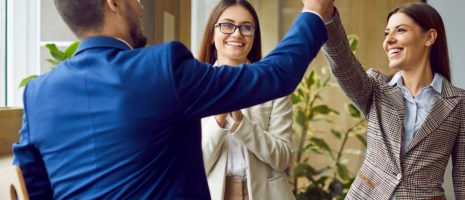 Three business professionals celebrating success in a modern office after completing a training program